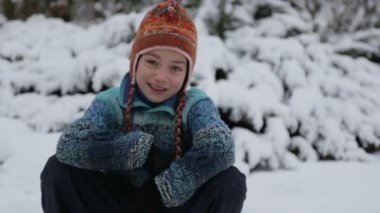 Karda parkta oynayan bir çocuk. Kışın erkek bir bebek portresi. Karda oynarken çocuk kameraya bir kartopu atar. 