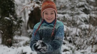Karda parkta oynayan bir çocuk. Kışın erkek bir bebek portresi. Karda oynarken çocuk kameraya bir kartopu atar. 