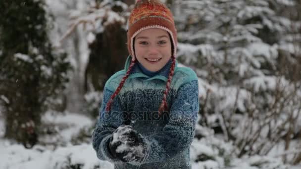 Een kind in het park in de sneeuw spelen. Portret van een babyjongen buiten in de winter. Jongen spelen in de sneeuw, gooit een sneeuwbal op de camera. — Stockvideo