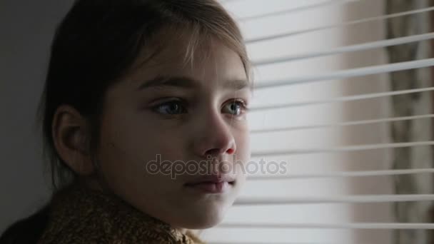 Portrait d'enfant à la fenêtre. Le garçon fait face à fermer l'enfant à travers le verre. Triste garçon regarde par la fenêtre . — Video