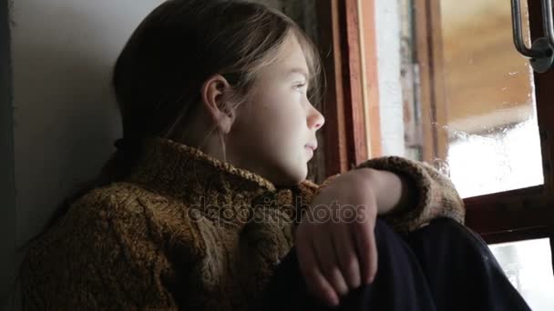 Portret van het kind in het venster. Het gezicht van de jongen is close-up van kind door middel van het glas. Trieste jongen kijkt uit het raam. — Stockvideo