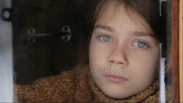 Retrato de niño en la ventana. El chico cara de cerca niño a través del vidrio. Chico triste mira por la ventana . — Vídeo de stock