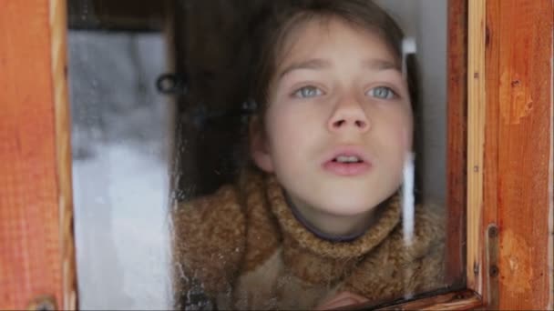 Portret van het kind in het venster. Het gezicht van de jongen is close-up van kind door middel van het glas. Trieste jongen kijkt uit het raam. — Stockvideo