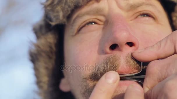 Портрет человека, играющего на арфе. Бородатый шаман играет на губной гармошке. Лицо крупным планом с еврейской арфой музыканта. Face close up with a musical instrument Jew 's Harp (Sound file ). — стоковое видео