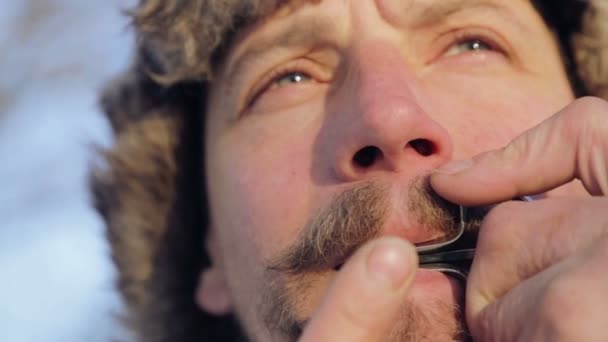 Portrait of a man playing a harp. The bearded shaman plays the harmonica drymba. Face closeup with a musician Jew's Harp. Face close up with a musical instrument Jew's Harp (Sound file). — Stock Video
