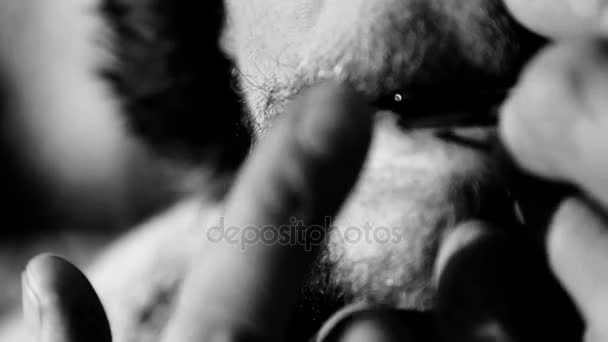 Portrait of a man playing a harp(black and white image). The bearded shaman plays the harmonica drymba(black and white image). Face close up with a musical instrument Jew's Harp (Sound file). — Stock Video