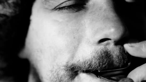 Portrait of a man playing a harp(black and white image). The bearded shaman plays the harmonica drymba(black and white image). Face close up with a musical instrument Jew's Harp (Sound file). — Stock Video