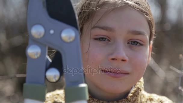 El niño corta los árboles en el jardín con una podadora. El niño ayuda a cortar los árboles en el parque en la primavera. Un jardinero adolescente corta ramas en la granja . — Vídeo de stock