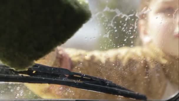 Kind jongen verdient geld op auto wassen. De jongen wast de Autoglas. Het kind helpt bij het wassen van de auto. — Stockvideo