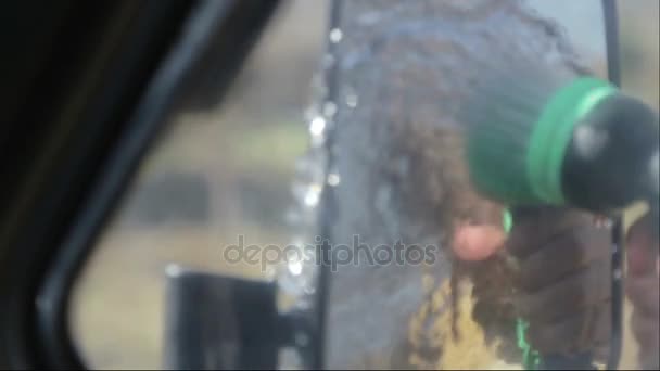 Chłopiec dziecko zarabia pieniądze na mycie samochodu. Chłopiec myje szybę samochodu. — Wideo stockowe