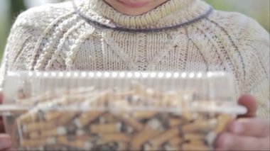 Çocuk sigara izmaritleri bir tabak içinde bakıyor. Bir genç sigara izmaritleri görünüyor. Anti tütün video. Sağlıklı bir yaşam tarzı için. 