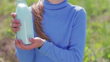 Bir çocuk portresi ile bir şişe süt bir çayırda. Bir çocuk bir alanda yakınındaki bir inek süt içiyor. Sağlıklı bir yaşam tarzı. Sağlıklı beslenme. 