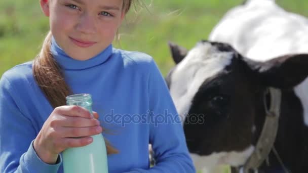 Porträt eines Jungen mit einer Flasche Milch auf einer Wiese. Ein Junge trinkt Milch in der Nähe einer Kuh auf einem Feld. Gesunder Lebensstil. Gesunde Ernährung. — Stockvideo