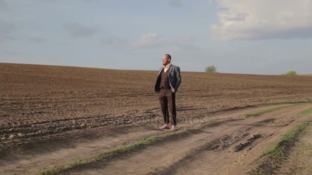 Hombre barbudo con traje en el campo descalzo. Un guapo barbudo camina por el campo. Hombre en un traje clásico en la naturaleza . — Vídeos de Stock