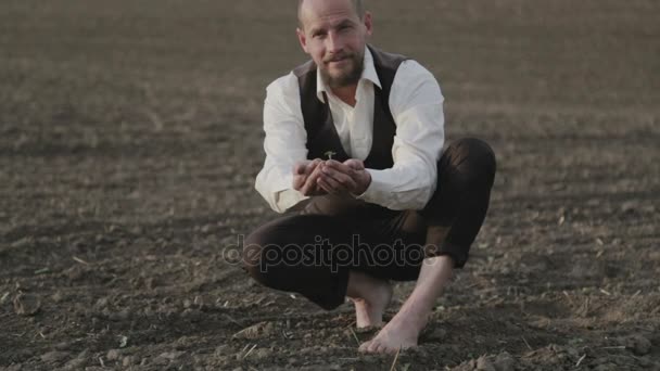 Vousatý farmář drží sazeničku v jeho rukou. Zemědělci manžel se dívá na sklizeň. Mohou agronomové zkoumá semena, které vzrostly. — Stock video