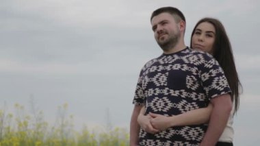 Genç bir çift bir alanda açık havada portresi. Erkek ve kadın Park bulutlar bir arka plan üzerinde. Genç bir aile doğada şehir dışında sorunları çözer. 