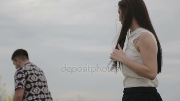 Retrato de una pareja joven al aire libre en un campo. Hombre y mujer sobre un fondo de nubes en el parque. Una familia joven resuelve problemas fuera de la ciudad en la naturaleza . — Vídeos de Stock