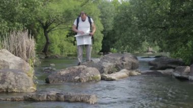 Adam adam seyahatleri boyunca nehir ford sakallı. Bir sırt çantası ile bir turist nehir geçiyor. Sakallı adam nehir geçiyor.