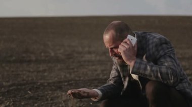 Sakallı bir toprak sahibi alanında telefonla konuşuyor. Takım elbiseli bir adam duygusal cep telefonunuzda konuşuyor. Alanında bir telefon ile bir sakallı.