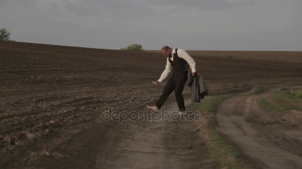 Male in a classic costume in nature. A man in a suit is glad and dances in the field. — Stock Video