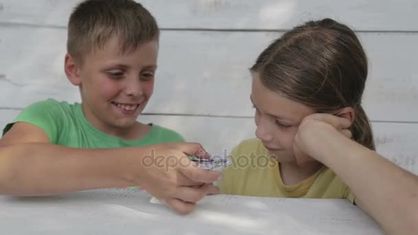 Los chicos están jugando con el spinner. Los amigos juegan juguete spinner. Dos hermanos en la calle juegan con un spinner . — Vídeos de Stock