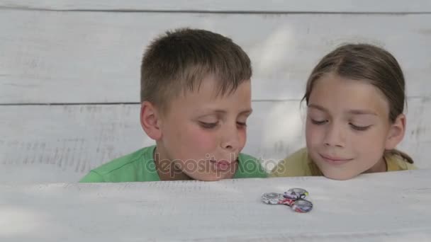 Los chicos están jugando con el spinner. Los amigos juegan juguete spinner. Dos hermanos en la calle juegan con un spinner . — Vídeos de Stock