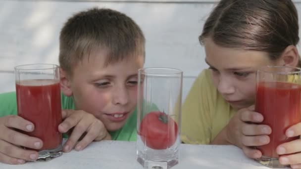 Los niños sobre el fondo blanco beben el jugo de tomate de los vasos. Dos chicos beben jugo de tomate. Harina natural, pienso saludable . — Vídeo de stock