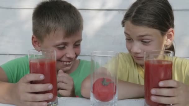 A fehér hátterű gyermekek inni paradicsomlé szemüveg. Két fiú inni paradicsomlé. Természetes ételek, egészséges takarmány. — Stock videók