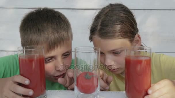 Los niños sobre el fondo blanco beben el jugo de tomate de los vasos. Dos chicos beben jugo de tomate. Harina natural, pienso saludable . — Vídeos de Stock