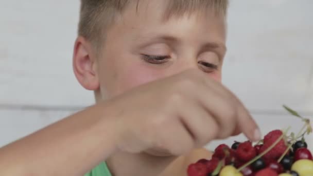 Retrato de chicos por CU de comer bayas. Los niños comen bayas frescas de un plato . — Vídeos de Stock