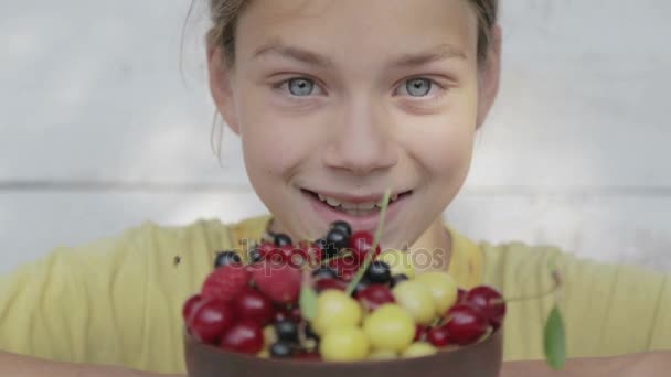 Uma criança come bagas frescas de um prato. Retrato de menino de comer bagas . — Vídeo de Stock