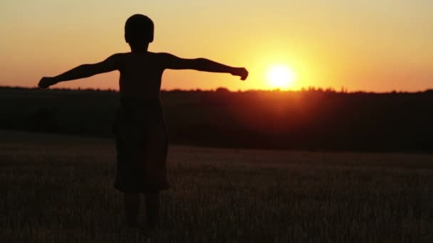 Der Junge bei Sonnenuntergang macht Übungen, die über das Feld laufen. das Kind bei Sonnenuntergang auf dem Feld rennt und macht Übungen.