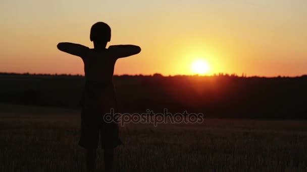 夕暮れ少年は、フィールドの周りを実行する演習を行います。フィールドの日の日没時子は実行、演習. — ストック動画