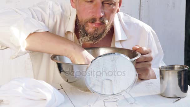 Um jovem cuida de sua barba enquanto está sentado em uma mesa. Retrato de um homem barbudo ocupado com a barba. Saúde, higiene, beleza . — Vídeo de Stock