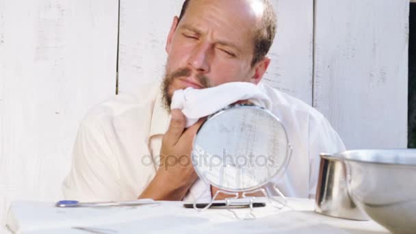 Mladý muž vypadá po vousech při sezení u stolu. Portrét vousatého muže plné ruce práce s vousy. Zdraví, hygiena, krása. — Stock video