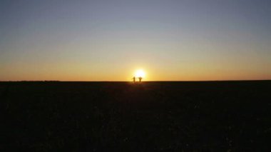 Erkek ve kadın gün batımında alanında. Bir kaç gün batımında çalışır ve alana atlar.