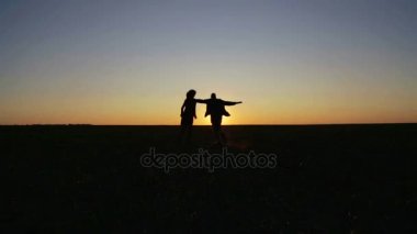 Erkek ve kadın gün batımında alanında. Bir kaç gün batımında çalışır ve alana atlar.