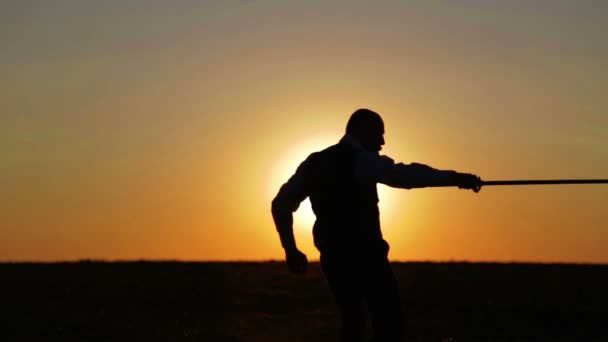 Porträt eines Mannes mit einem Schwert bei Sonnenuntergang, der Weg eines Kriegers. Samurai-Yakuza mit einem Schwert bei Sonnenuntergang. Sport, Hobbys, Interessen. — Stockvideo