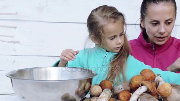 Mutter und Tochter säubern frisch gepflückte Pilze. Porträt einer Mutter mit ihrem Kind bei der Reinigung ökologisch sauberer Lebensmittel. Essen, Kochen, Umweltfreundlichkeit. — Stockvideo