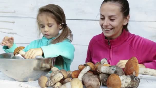 妈妈和女儿清洁新鲜采摘的蘑菇。一位母亲和她的孩子为清洗生态清洁食品的画像。食、 煮食、 环境友好性. — 图库视频影像