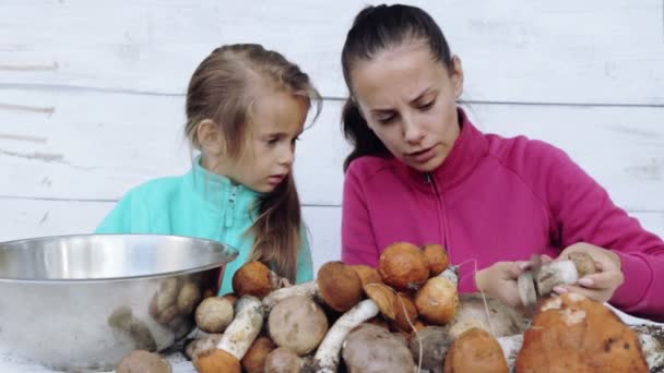 Mamma e figlia pulite funghi appena raccolti. Ritratto di una madre con suo figlio per la pulizia di alimenti ecologicamente puliti. Cibo, cucina, rispetto dell'ambiente . — Video Stock