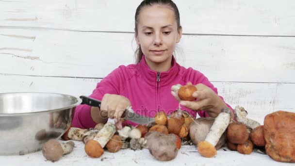 Mulher bonita nova limpando cogumelos frescos. Retrato de uma jovem cozinheira preparando cogumelos. Uma cozinha natural e ecológica . — Vídeo de Stock