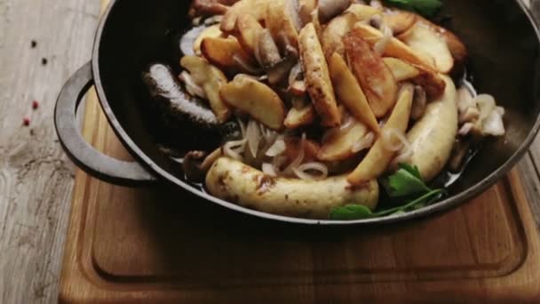 Sausages cooked on a barbecue with potatoes and mushrooms. A restaurant dish of sausages with potatoes and mushrooms. — Stock Video