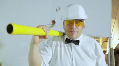 Oluşturucu bir balyoz ve bir kalem ile kameraya gider. Bir adam bir inşaat sitesinde kurucusudur.