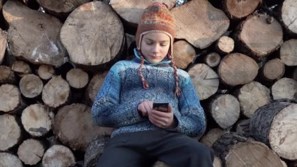 木の近くの村でのスマート フォンでやっている少年 ゲームの でスマート フォンでビデオを再生するファームでティーンエイ ジャー — ストック動画