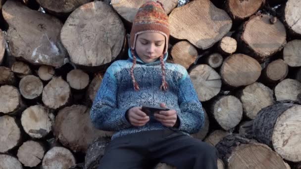 木の近くの村でのスマート フォンでやっている少年 ゲームの でスマート フォンでビデオを再生するファームでティーンエイ ジャー — ストック動画