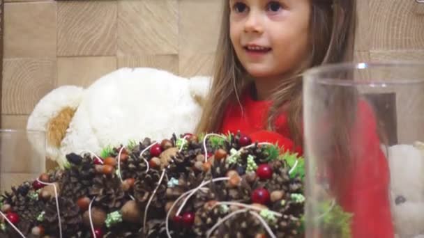 少女は 休日のクリスマス リースを作る 子供はクリスマスと新年の花輪で飾られています — ストック動画