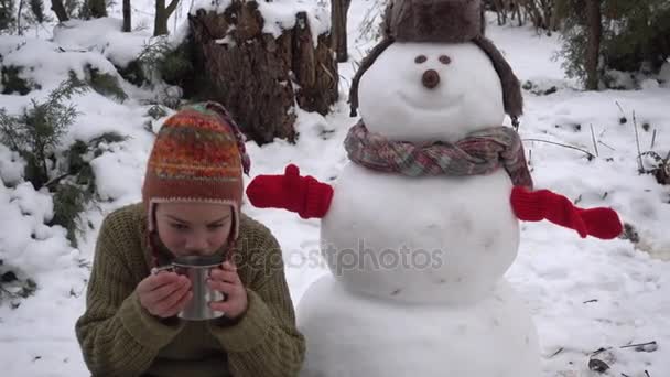 Ένα Αγόρι Πίνει Τσάι Κοντά Έναν Χιονάνθρωπο Χειμώνα Στο Δρόμο — Αρχείο Βίντεο