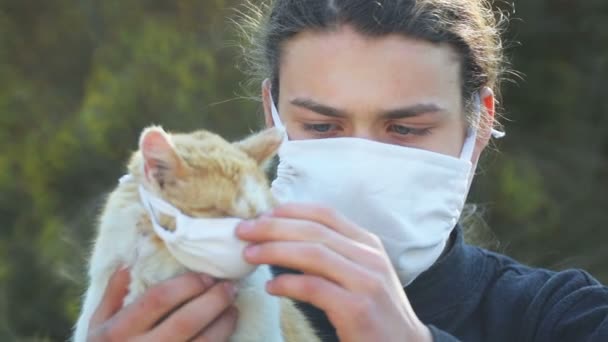 ウィルスのマスクを着た10代の少年と猫 少年はマスクで猫をウイルスから守る — ストック動画