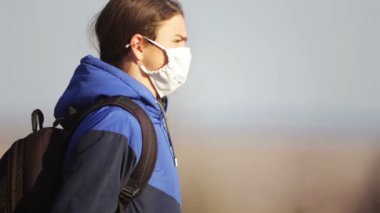 Karantinadan sonra genç bir çocuk doğada maskeyle yürüyor. Tabiat maskeli bir gencin portresi.. 